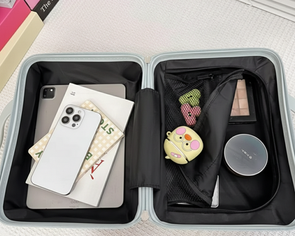 Open travel case with phone, books, and small items on a textured surface